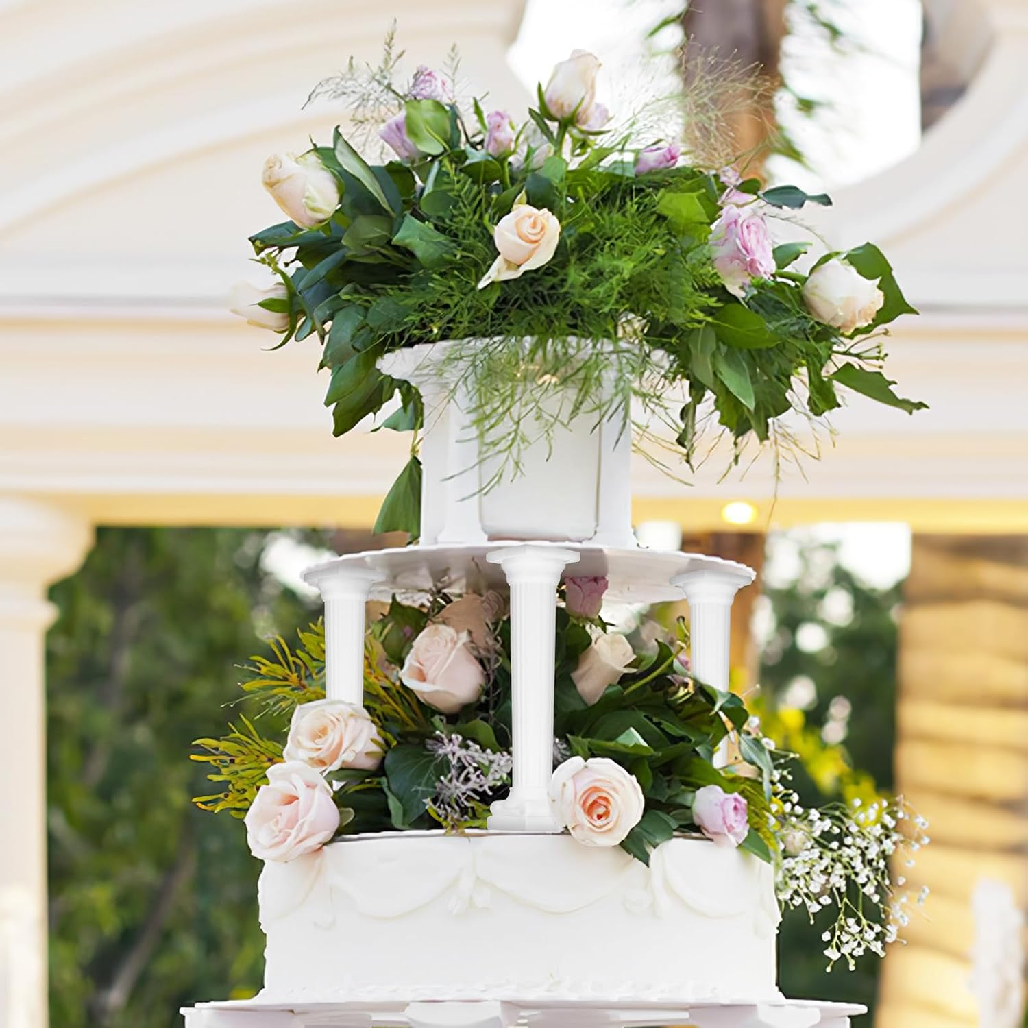 Floral wedding cake displayed with white decorative pillars
